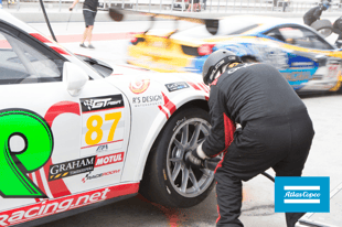 Pit crew with pneumatic tools putting a tire on car