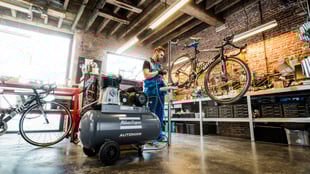 Image of an engineer fixing a bike with a compressor