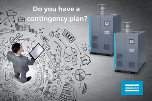 A man looking at a plan with two atlas copco compressors