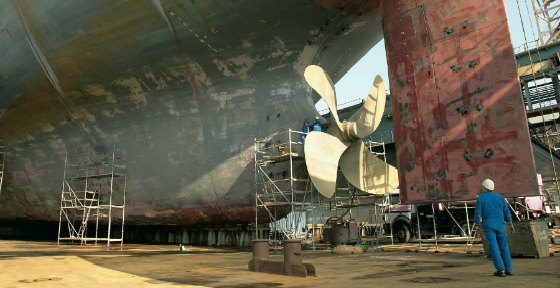 Wild angle image of a person and a cargo ship rudder.