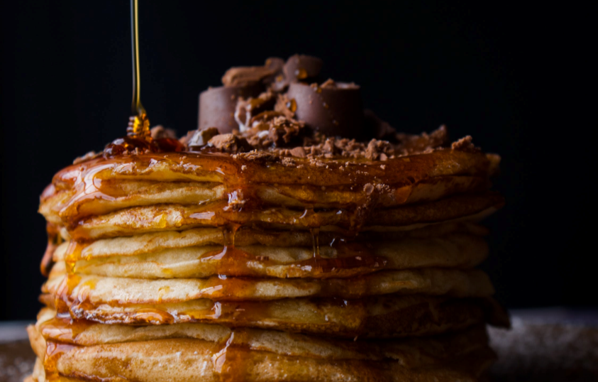 maply syrup being poured on pancakes